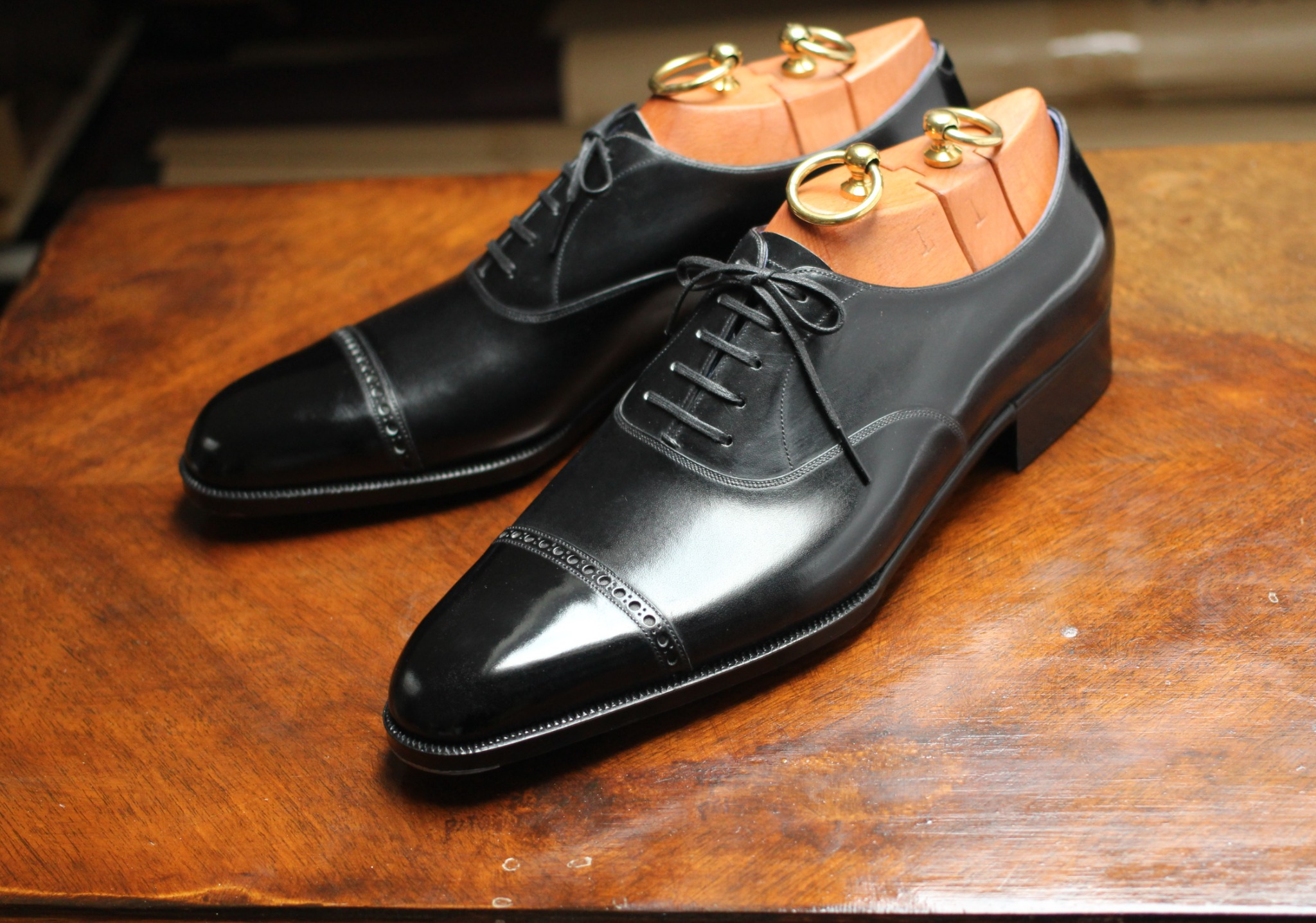 Black cap-toe Oxford shoes with brogued cap seam