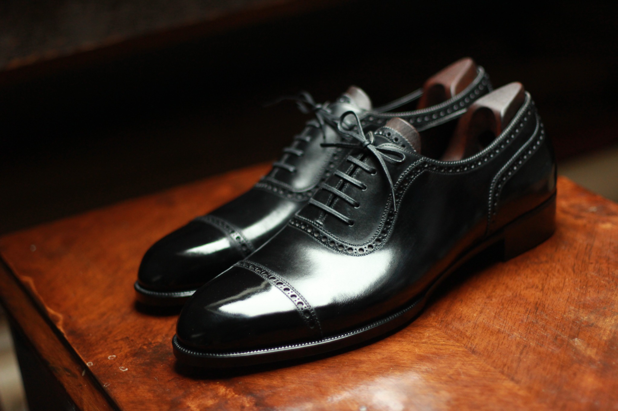 Black bespoke cap-toe Oxford shoes with brogue detailing
