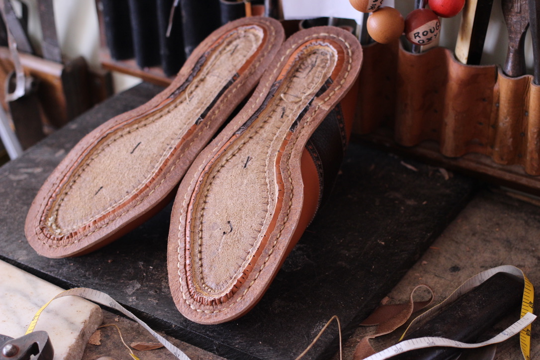 Hand-welted bespoke shoes in progress on a traditional shoemaking workbench